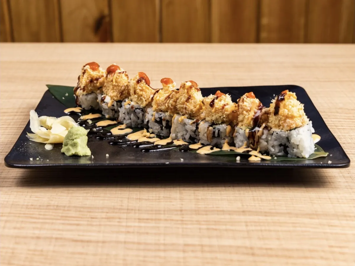 Hot Night Roll under a baked spicy crab topping with sriracha dots, spicy mayo and eel sauce