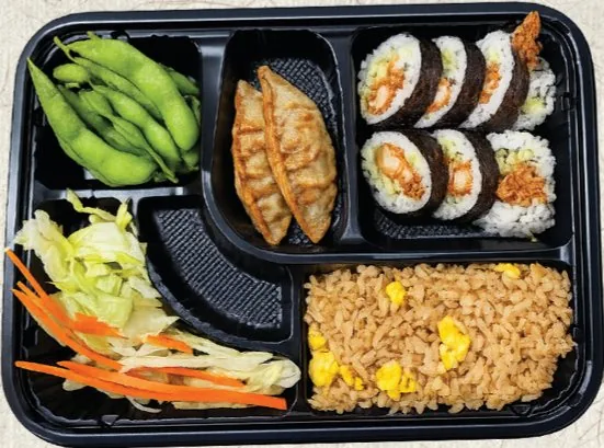 Lunch bento box with edamame, gyoza, sushi roll, pickles and fried rice
